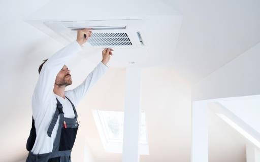 AC maintenance technician servicing ceiling unit